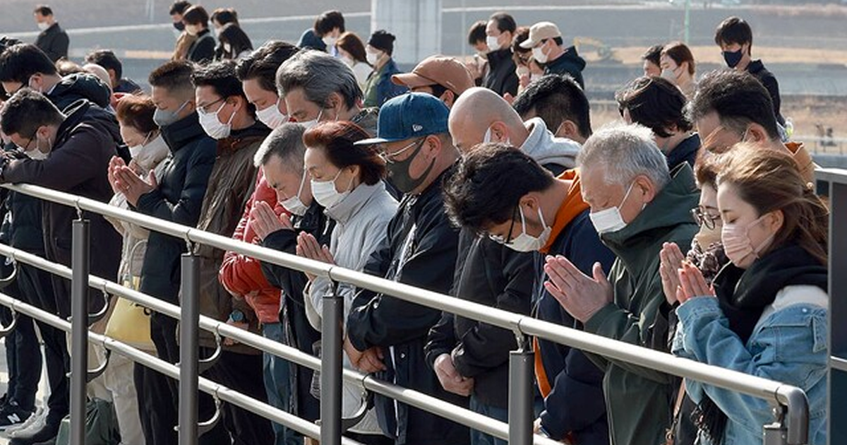 東日本大震災の発生時刻に合わせて「奇跡の一本松」を背に黙とうする人たち＝１１日午後２時４６分、岩手県陸前高田市